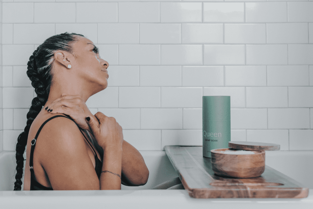 A woman taking a bath with Unplugged Essentials Queen Soak while massaging her own neck.