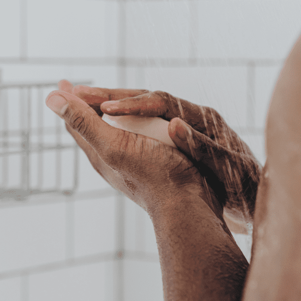 A man's hands clasp on the king body bar in the shower.