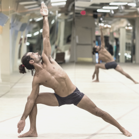A man performing hot yoga in a studio alone.